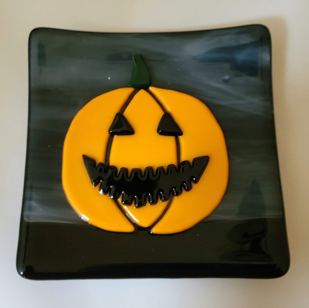 A glass plate with a smiling pumpkin face design.